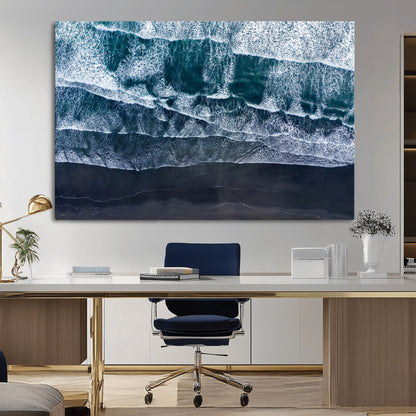 Canvas of aerial ocean waves crashing onto a black sand beach in moody tones, ideal for modern coastal or minimalist home decor.