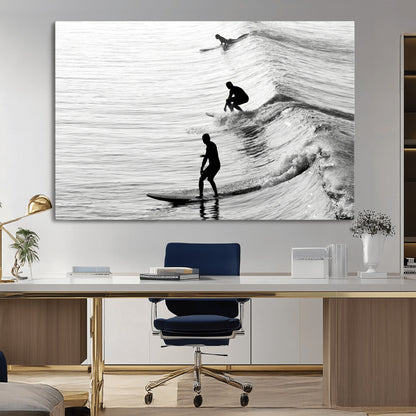 Black and white photo of surfers riding waves in a moody, high-contrast scene, ideal for modern coastal or surf-inspired home decor.