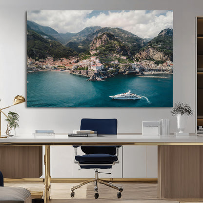 Aerial view of Amalfi Coast, Italy, with colorful hillside houses, lush green mountains, and a luxury yacht sailing in turquoise waters.