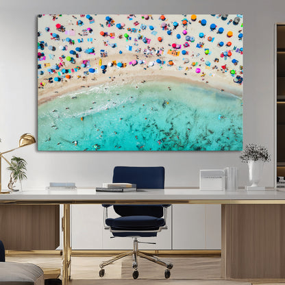 Aerial view of a vibrant beach filled with colorful umbrellas and people enjoying the turquoise ocean, capturing a lively summer vacation scene.