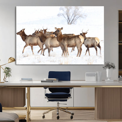 A group of elk standing on snowy terrain with a tree in the background, perfect for rustic or lodge-style winter wall decor.