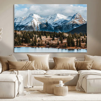 Framed canvas of snowy mountain peaks with pine forest and alpine lake, perfect for winter cabin or wilderness-inspired home decor.