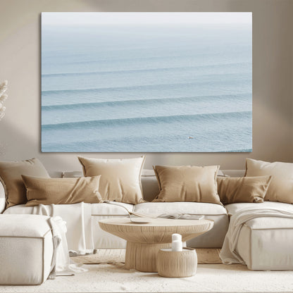 Framed canvas of repeating ocean waves with a distant solo surfer, ideal for minimalist ocean or calm coastal wall decor.