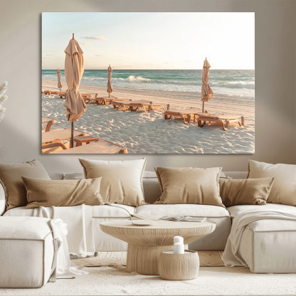 Minimalist photo of empty beach loungers and umbrellas on soft sand, ideal for calm seaside or pastel coastal-style home decor.