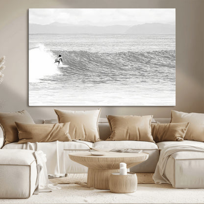 Monochrome photo of a surfer riding a wave with distant mountains, ideal for coastal motion or black and white surf-themed wall decor.