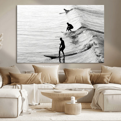 Black and white photo of surfers riding waves in a moody, high-contrast scene, ideal for modern coastal or surf-inspired home decor.