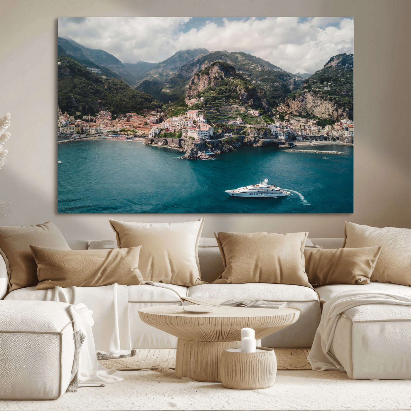 Aerial view of Amalfi Coast, Italy, with colorful hillside houses, lush green mountains, and a luxury yacht sailing in turquoise waters.