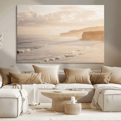 Golden hour seascape with misty cliffs and gentle waves rolling towards the shore, capturing a tranquil and warm coastal atmosphere.