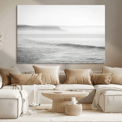 A black and white minimalist seascape featuring soft rolling waves and misty distant cliffs, creating a serene and timeless coastal atmosphere.