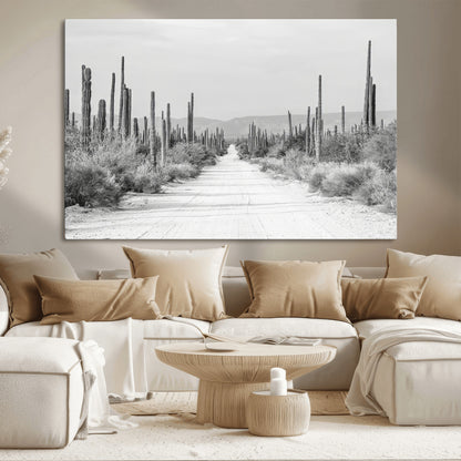A black and white desert road stretching through a cactus-filled landscape, creating a rugged and timeless southwestern aesthetic with a sense of adventure.