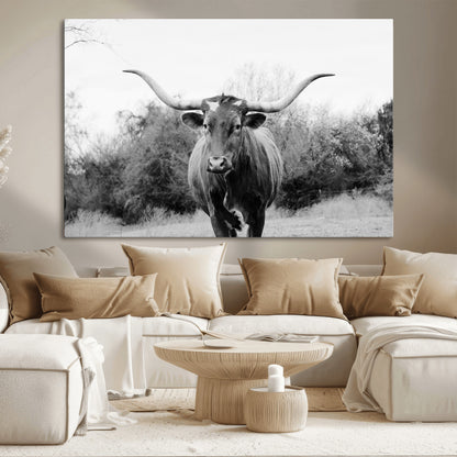 Black and white photo of a longhorn cow in a field, perfect for rustic farmhouse or western-themed interior wall decoration.
