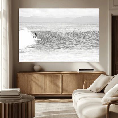 Monochrome photo of a surfer riding a wave with distant mountains, ideal for coastal motion or black and white surf-themed wall decor.