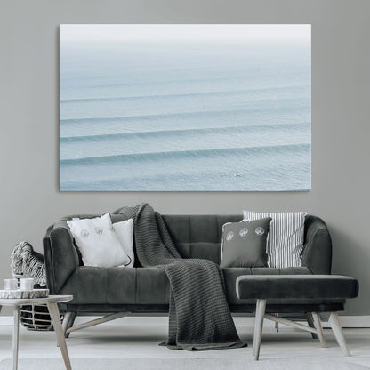 Framed canvas of repeating ocean waves with a distant solo surfer, ideal for minimalist ocean or calm coastal wall decor.