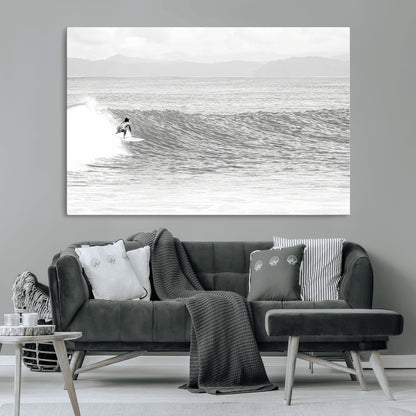 Monochrome photo of a surfer riding a wave with distant mountains, ideal for coastal motion or black and white surf-themed wall decor.