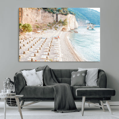 Wall art of a calm Mediterranean beach with rows of sun loungers and umbrellas in soft pastel tones, perfect for light coastal or vacation-themed decor.