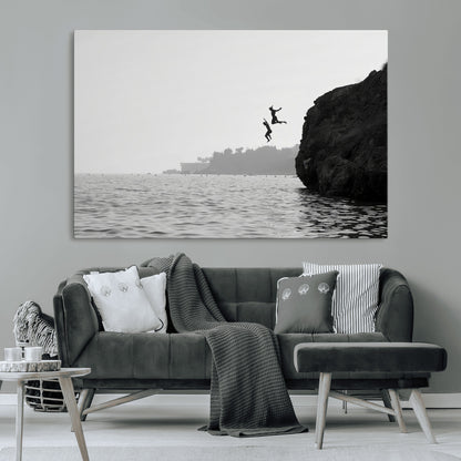 Black and white canvas of two figures cliff jumping into the sea, captured with moody tones, ideal for modern coastal or adventure-themed home decor.   2/2