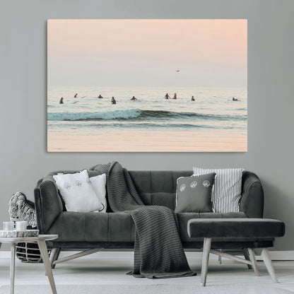 Dreamy photo of surfers waiting on soft pastel waves under a pink sunset sky, ideal for soft coastal minimalist or serene ocean-themed home decor.