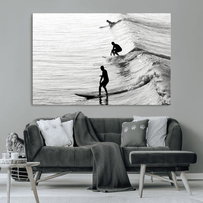 Black and white photo of surfers riding waves in a moody, high-contrast scene, ideal for modern coastal or surf-inspired home decor.