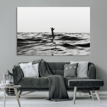 Black and white ocean with a hand making a surfer sign among dark waves, creating a dramatic and minimalist seascape with bold contrast.