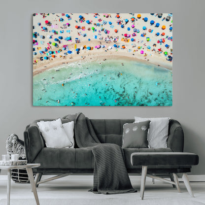 Aerial view of a vibrant beach filled with colorful umbrellas and people enjoying the turquoise ocean, capturing a lively summer vacation scene.