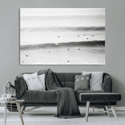 A monochrome photograph of swimmers gliding through gentle ocean waves, evoking a sense of calm and movement.