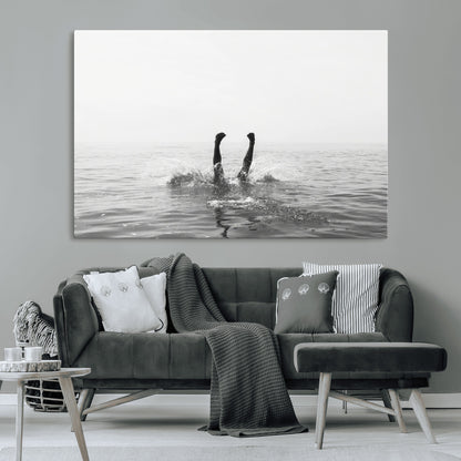 A black and white minimalist water scene capturing a playful splash as a swimmer dives upside down, creating a carefree and artistic aquatic aesthetic.