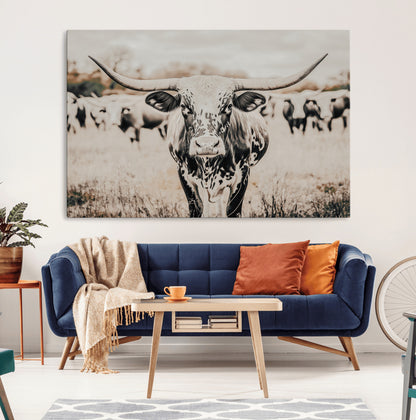 Canvas of a speckled Texas longhorn standing boldly in a field with a herd behind, perfect for rustic western or farmhouse wall decor.