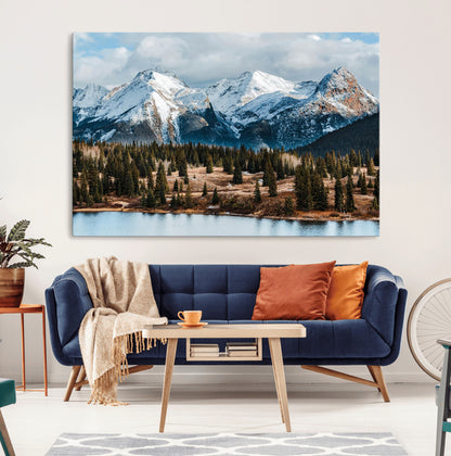 Framed canvas of snowy mountain peaks with pine forest and alpine lake, perfect for winter cabin or wilderness-inspired home decor.