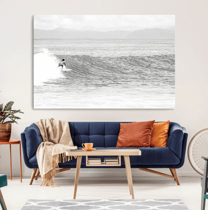 Monochrome photo of a surfer riding a wave with distant mountains, ideal for coastal motion or black and white surf-themed wall decor.