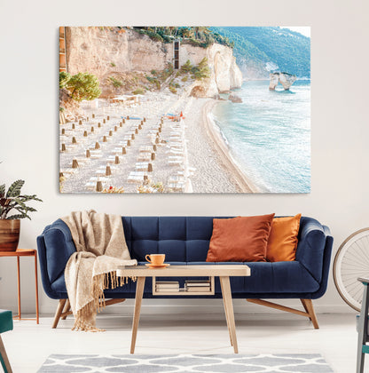 Wall art of a calm Mediterranean beach with rows of sun loungers and umbrellas in soft pastel tones, perfect for light coastal or vacation-themed decor.