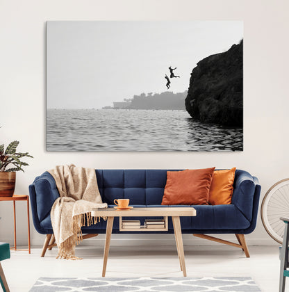Black and white canvas of two figures cliff jumping into the sea, captured with moody tones, ideal for modern coastal or adventure-themed home decor.   2/2