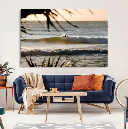 Photo of a surfer riding a golden hour wave at sunset, with tropical tones and dreamy light, perfect for tropical boho or coastal home decor.