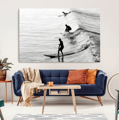 Black and white photo of surfers riding waves in a moody, high-contrast scene, ideal for modern coastal or surf-inspired home decor.
