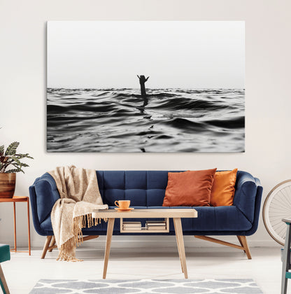 Black and white ocean with a hand making a surfer sign among dark waves, creating a dramatic and minimalist seascape with bold contrast.