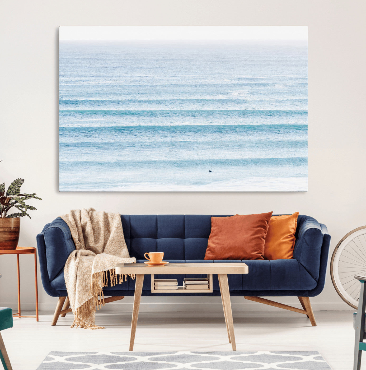 Minimalist ocean view with soft blue waves and a lone surfer, creating a serene and airy coastal aesthetic, perfect for tranquil home decor.
