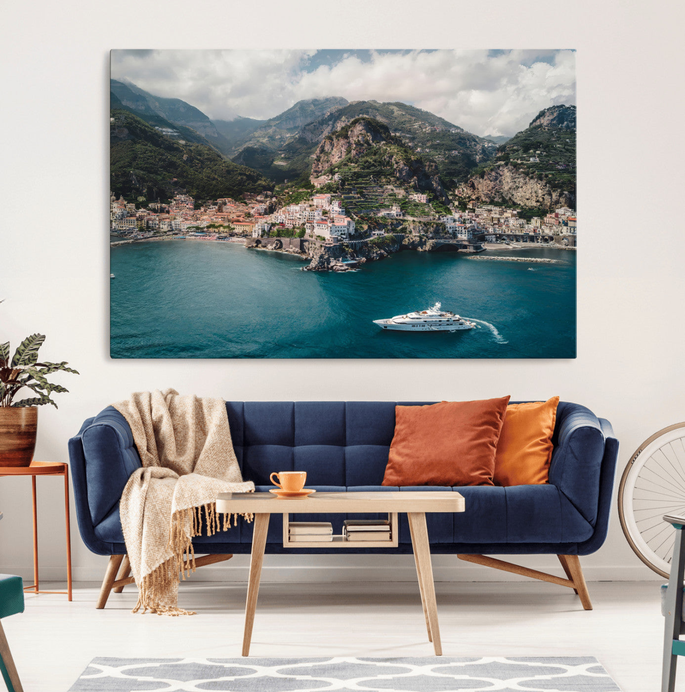 Aerial view of Amalfi Coast, Italy, with colorful hillside houses, lush green mountains, and a luxury yacht sailing in turquoise waters.