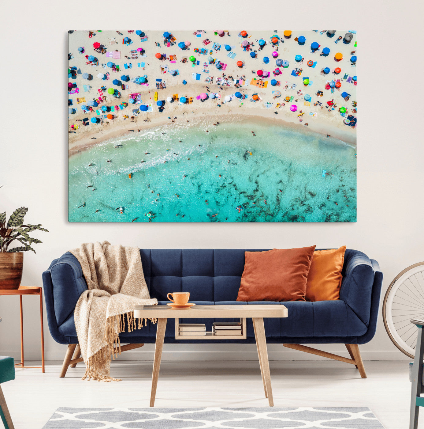 Aerial view of a vibrant beach filled with colorful umbrellas and people enjoying the turquoise ocean, capturing a lively summer vacation scene.