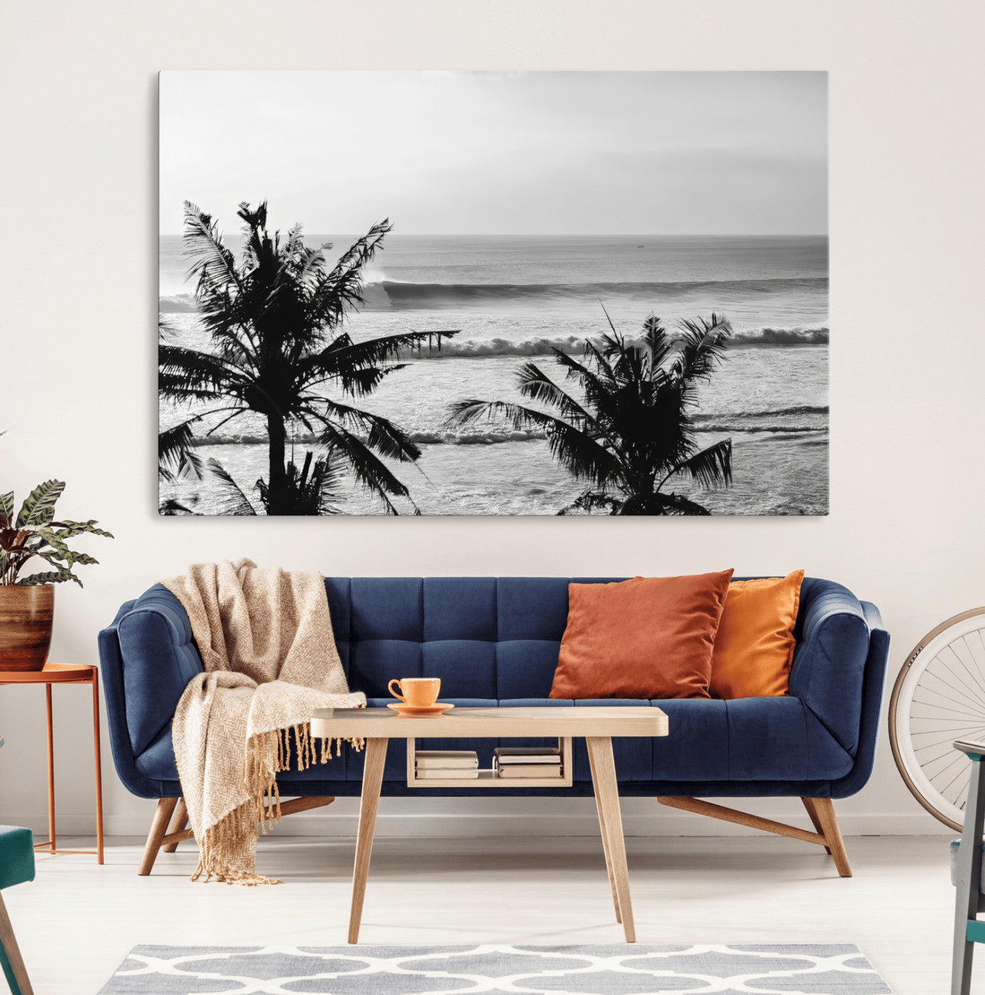 Black and white view of ocean waves crashing on a tropical coastline, framed by silhouetted palm trees under a vast, open sky.
