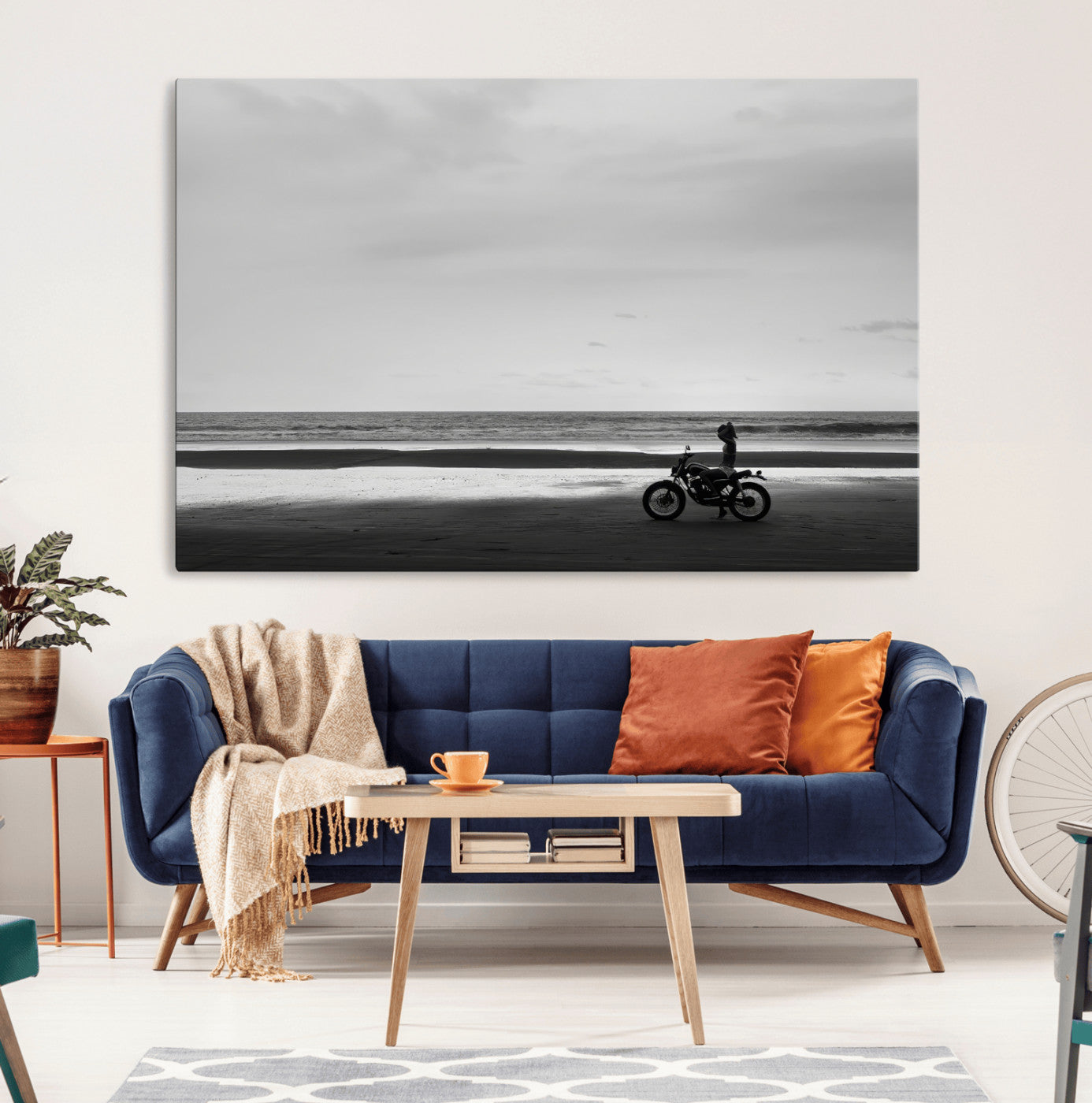 A motorcyclist on a vast beach, gazing at the ocean, capturing a moody and tranquil coastal adventure in black and white.