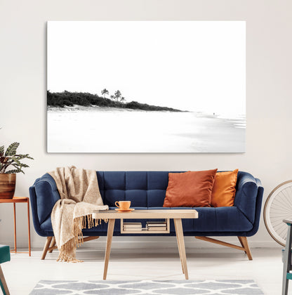 A black and white minimalist coastal scene with a vast open beach, distant palm trees, and a lone figure walking along the shoreline, evoking serenity and solitude.
