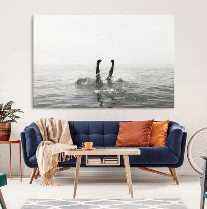 A black and white minimalist water scene capturing a playful splash as a swimmer dives upside down, creating a carefree and artistic aquatic aesthetic.