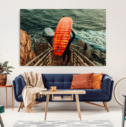 A surfer carrying a bold orange surfboard down a rugged staircase toward the ocean, bathed in golden hour light, capturing the energy of coastal adventure.