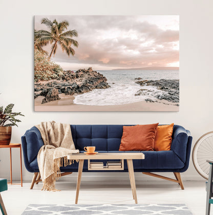 A peaceful beach scene with a palm tree and rocks, soft waves washing onto the shore under a soft pastel sky at sunset.