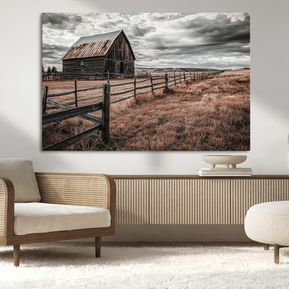 Framed canvas of a rustic barn under a moody sky with weathered fence and dark fields, ideal for farmhouse or rural-style wall decor.
