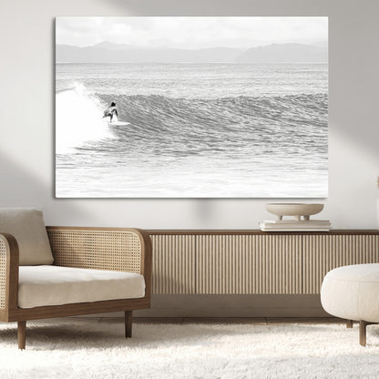 Monochrome photo of a surfer riding a wave with distant mountains, ideal for coastal motion or black and white surf-themed wall decor.