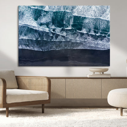 Canvas of aerial ocean waves crashing onto a black sand beach in moody tones, ideal for modern coastal or minimalist home decor.