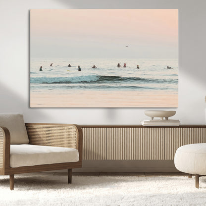 Dreamy photo of surfers waiting on soft pastel waves under a pink sunset sky, ideal for soft coastal minimalist or serene ocean-themed home decor.