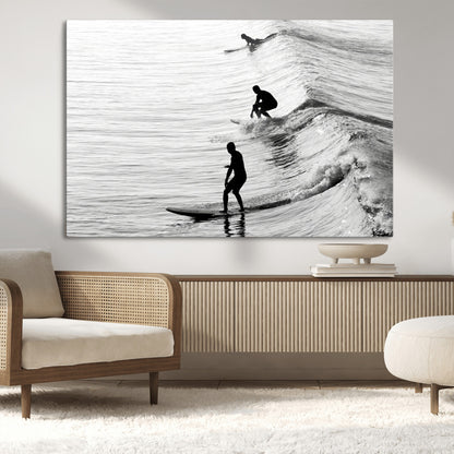 Black and white photo of surfers riding waves in a moody, high-contrast scene, ideal for modern coastal or surf-inspired home decor.