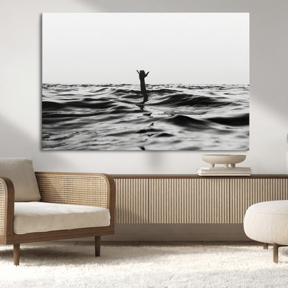 Black and white ocean with a hand making a surfer sign among dark waves, creating a dramatic and minimalist seascape with bold contrast.