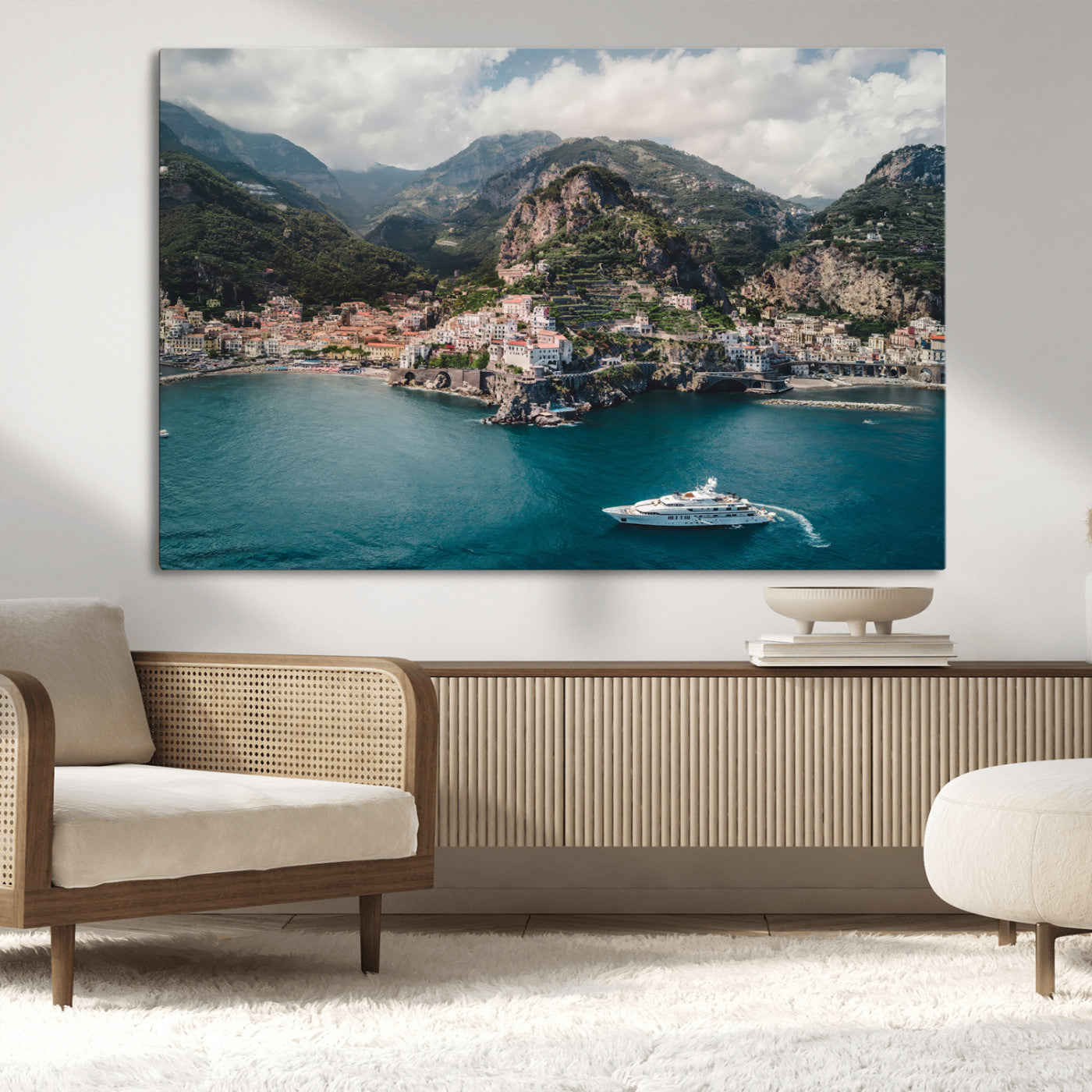 Aerial view of Amalfi Coast, Italy, with colorful hillside houses, lush green mountains, and a luxury yacht sailing in turquoise waters.